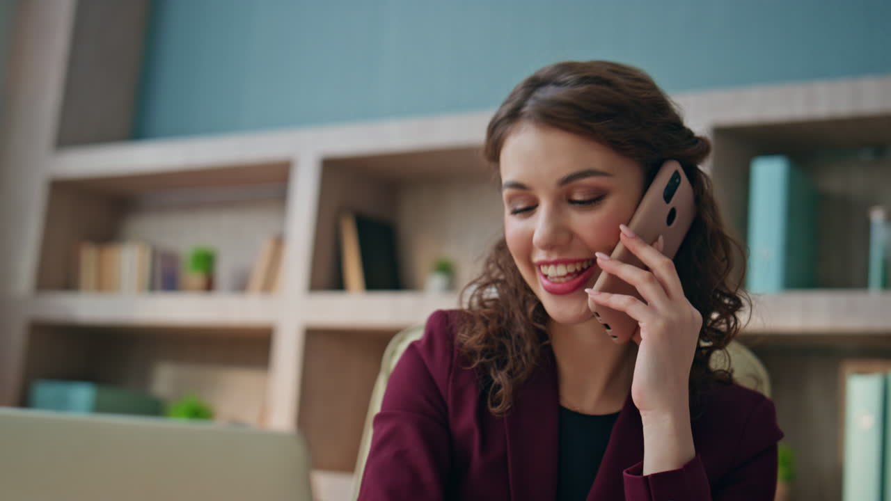 Employee calling mobile phone at desk closeup. Smiling woman having conversation