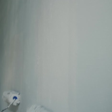 two people paint the wall with painting rollers