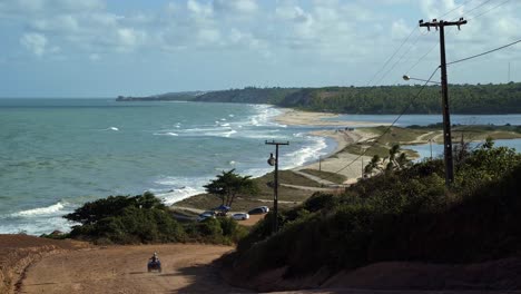 gramame beach where the ocean meets the large river with waves crashing into the sand and a four wheeler driving down the dirt road, near the beach capital city of joao pessoa in paraiba, brazil