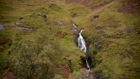 una cascada que fluye por la ladera de la montaña en las tierras altas de escocia