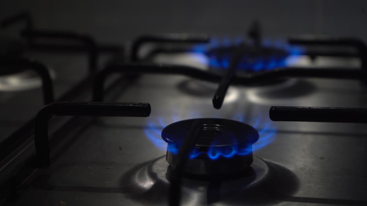 좁은 초점:가스 스토브에 있는 두 개의 버너가 뜨거운 푸른 불꽃으로 켜집니다.