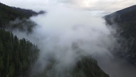 Flying-towards-clouds-with-a-view-over-a-lake,-mountain-and-a-forest