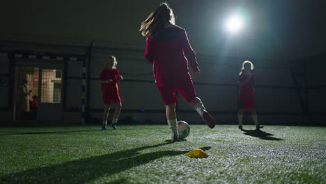 young girls practice indoor soccer at night