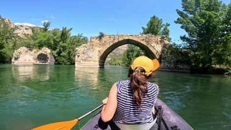 kayaking towards an ancient stone bridge on a clear day