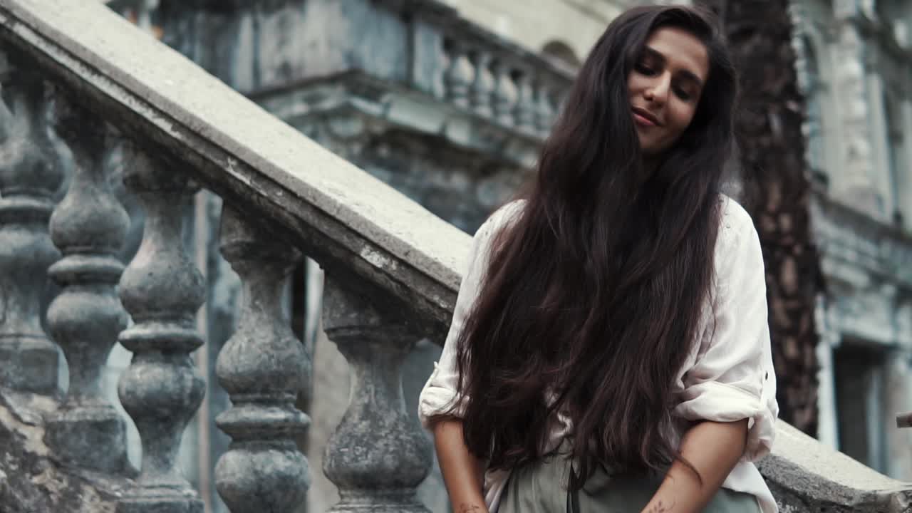mujer con cabello largo posando en escaleras de piedra
