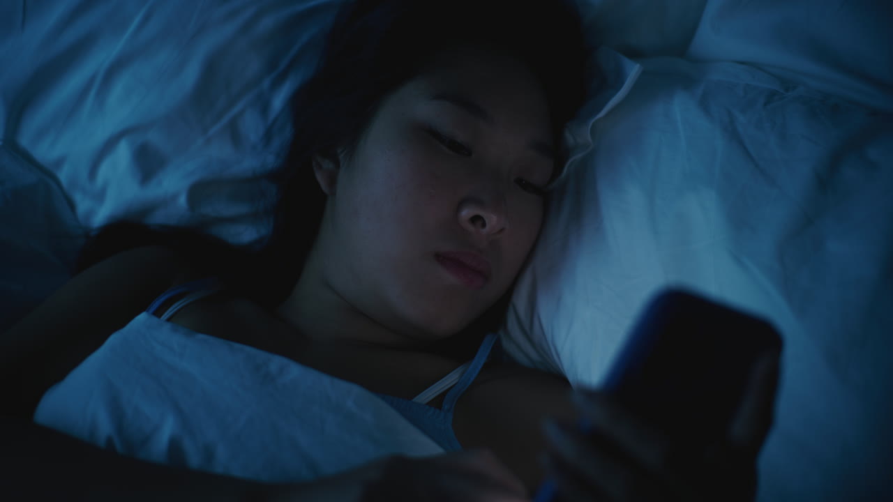 Woman using smartphone in bed at night