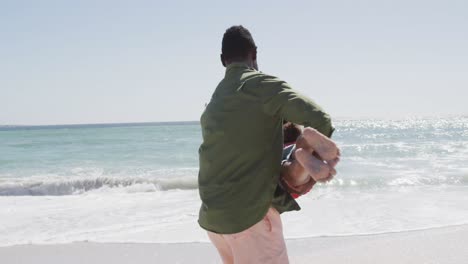 padre afroamericano sonriente con su hija jugando en una playa soleada