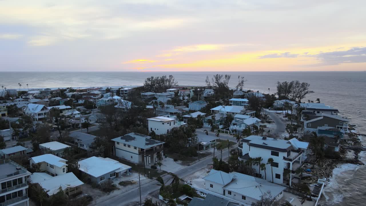 Aerial of Anna Maria Island, Florida at sunset revealing hurricane damage to waterfront homes. Crane Up Sunset W