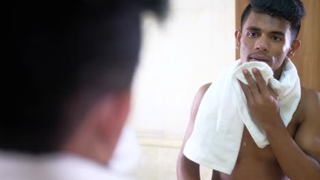 young man drying his face with a towel in the bathroom