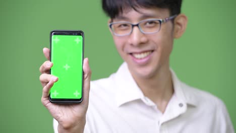 young asian businessman showing phone to camera