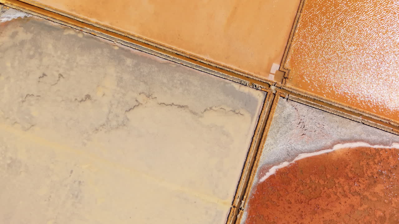Aerial drone shot of colorful salt pans in Sicily, Italy, unique geometric shapes with red, orange and yellow tones