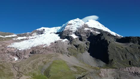 Aerial drone footage of the majestic Ausangate peak in the Peruvian Andes. Its snow-covered summit rises above rugged terrain, surrounded by pristine wilderness and dramatic high-altitude beauty