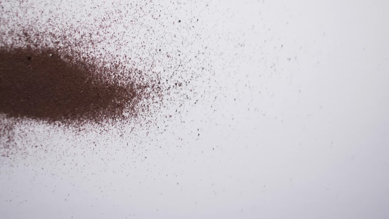 Video in primo piano di granelli di sabbia marrone e spazio per il testo su sfondo bianco.