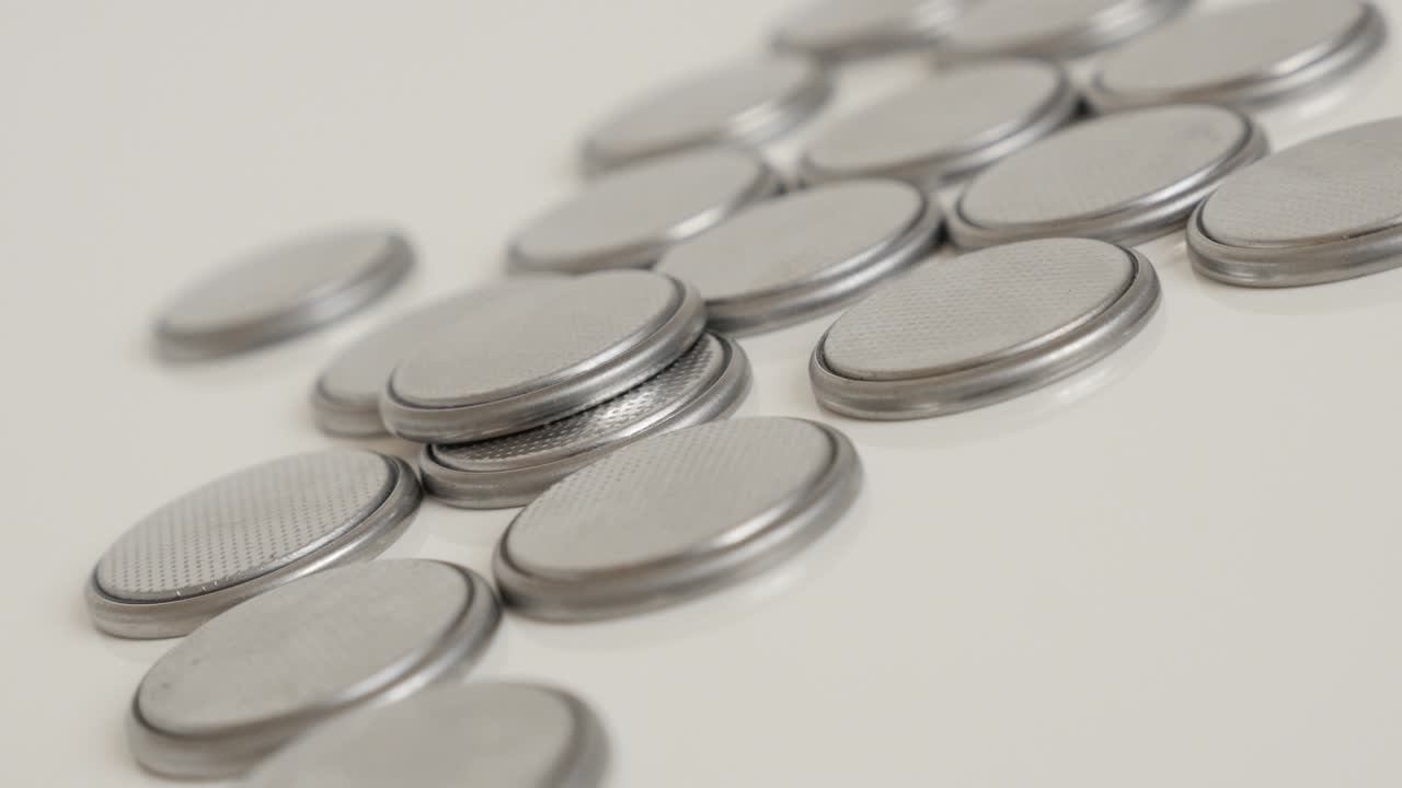 Pile of watch batteries close-up slow tilt 4K video