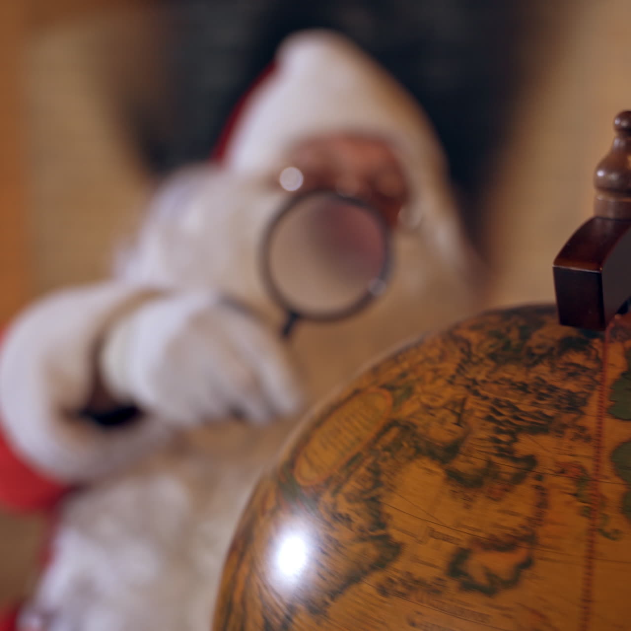 Santa Claus with globe. Big round globe and Santa looking at it through the magnifying glass. Close-up.