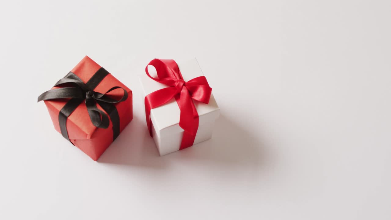 video de cajas de regalo blancas y rojas atadas con cintas, sobre fondo blanco con espacio para copiar