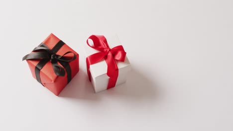 Video-of-white-and-red-gift-boxes-tied-with-ribbons,-on-white-background-with-copy-space