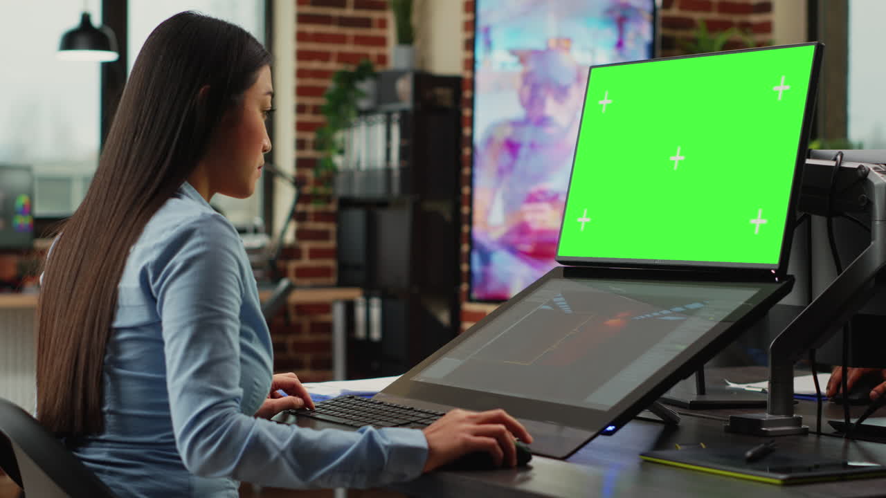 Female office worker using game developing interface and greenscreen display