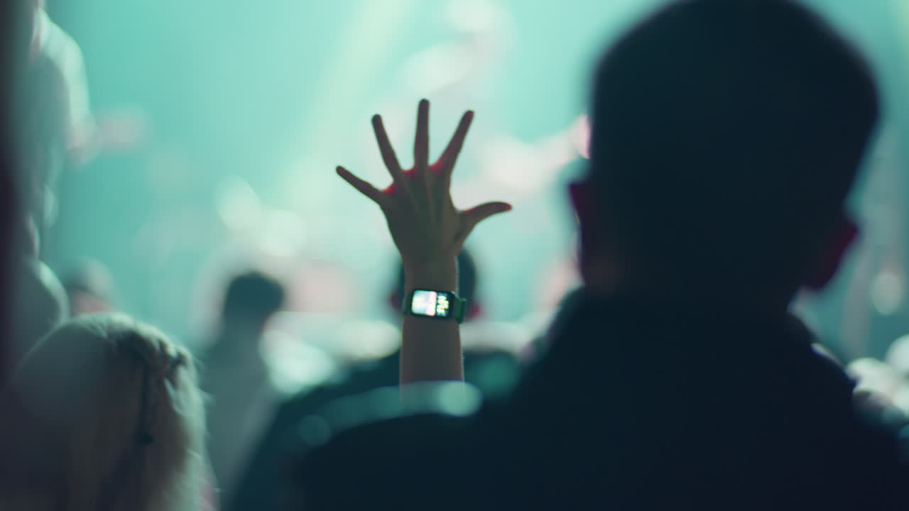 Person's Hand with Smartwatch Waving at a Lively Concert