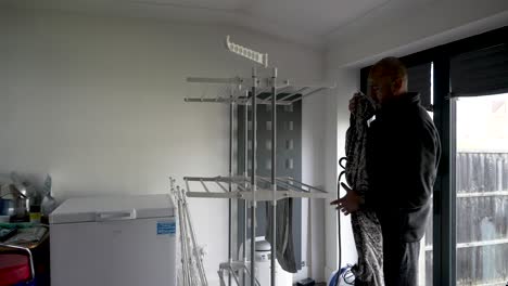 el marido de la casa en un entorno doméstico cuelga la ropa en un aireador interior, encarnando el concepto de lavandería interior y tareas domésticas diarias