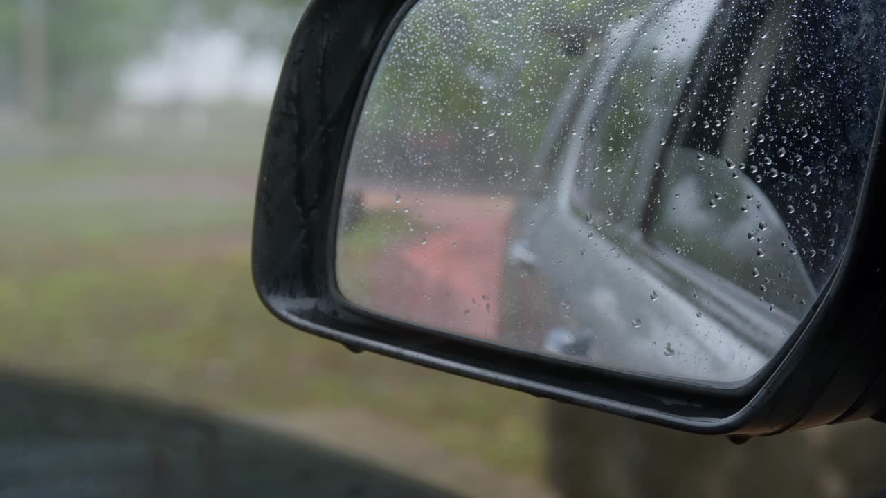 A monsoon storm lashes a community. Heavy rain and wind in remote northern Australia. Viewed from a vehicle side mirror