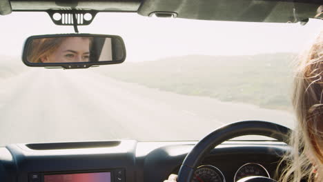 Two-women-driving-with-sunroof-open-looking-at-each-other