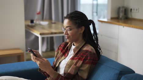 young woman using smartphone at home on a couch