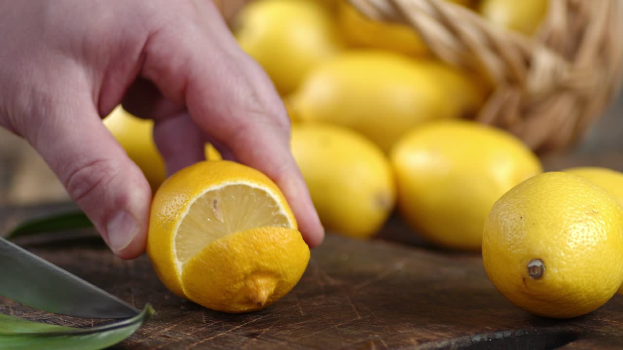 La mano di un uomo con un coltello taglia un limone fresco