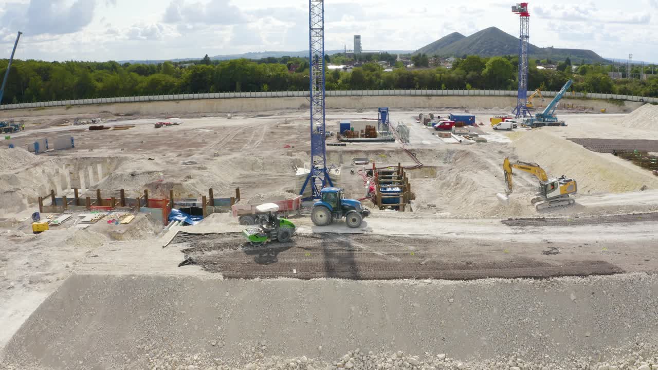 drone aéreo inclinado hacia abajo disparado sobre tractores que transportan suelo de un sitio de construcción en un día soleado