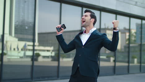 Hombre-De-Cerca-Usando-Un-Teléfono-Inteligente-En-La-Calle.-Empresario-Celebrando-La-Victoria-Al-Aire-Libre