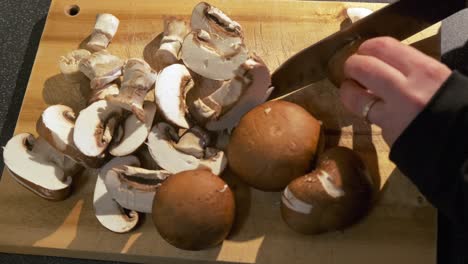 cerca de los hongos frescos siendo cortados por una mano de mujer preparando una receta saludable