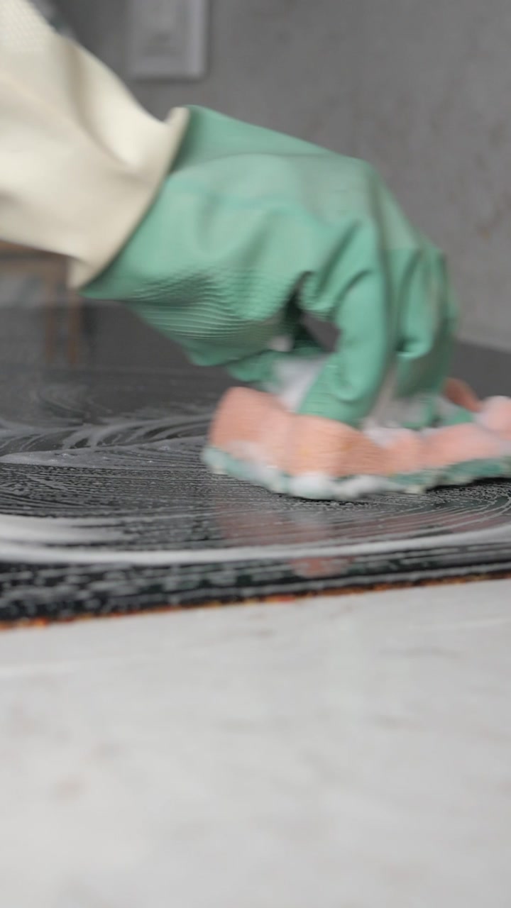 Gloved Hand Cleaning Stovetop with Foamy Sponge