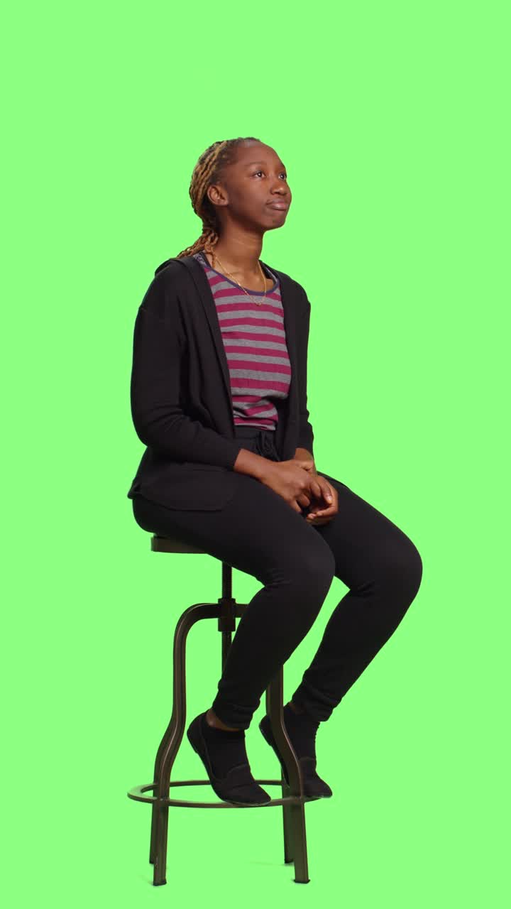 Video verticale: donna rilassata che aspetta seduta su una sedia con sfondo greenscreen integrale