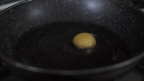 two eggshells being cracked into frying pan