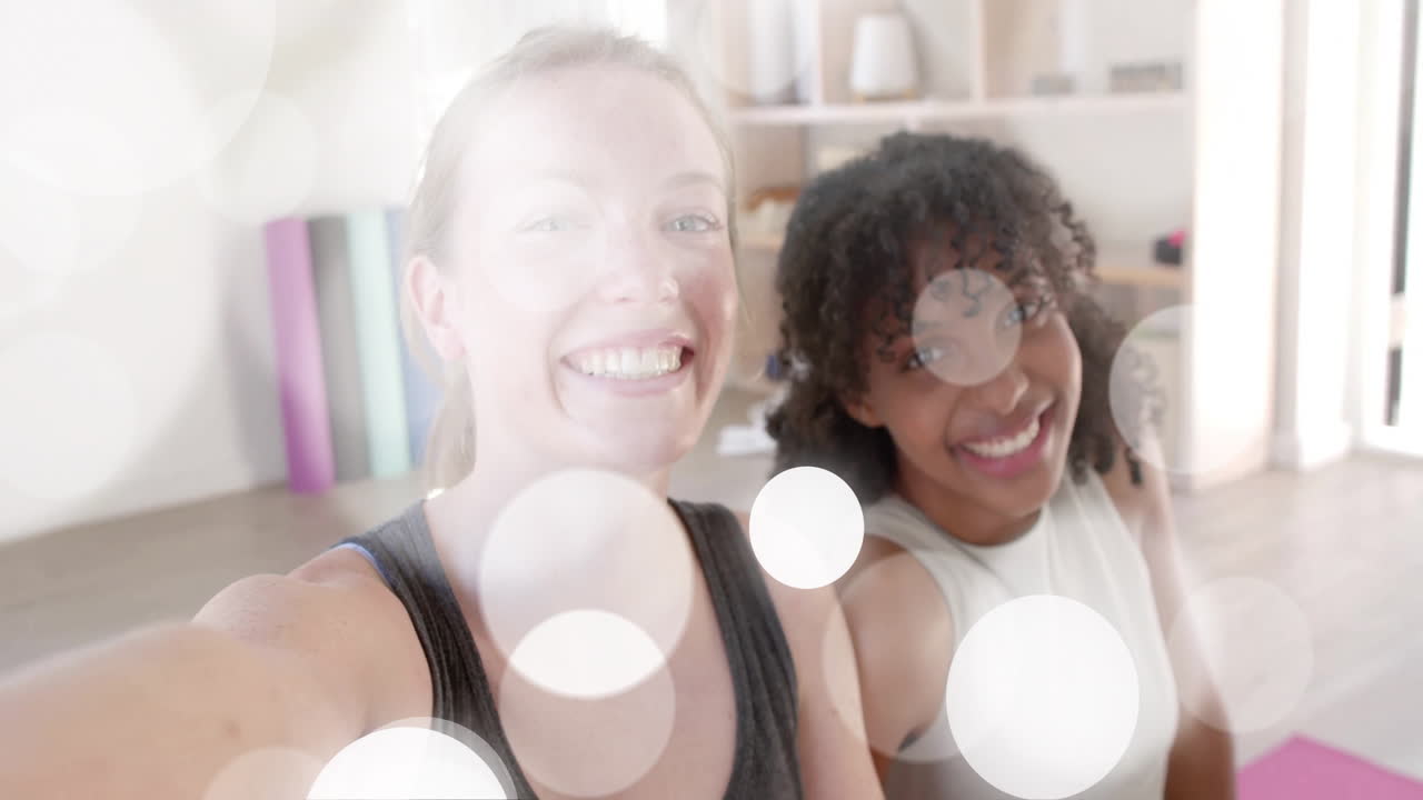 animación de manchas de luz blanca sobre felices adolescentes diversas tomando selfies en la clase de yoga