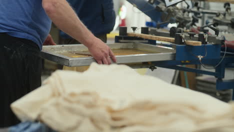 man places t shirt on screen printing machine