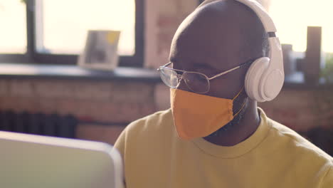 Portrait Of An Man With Headphones And Face Mask Working On Computer In An Animation Studio