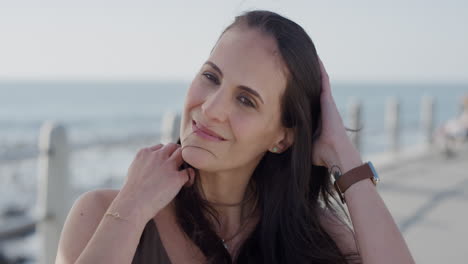 retrato de una hermosa mujer madura sonriendo disfrutando de la soleada playa corriendo con la mano a través del cabello en cámara lenta relajada