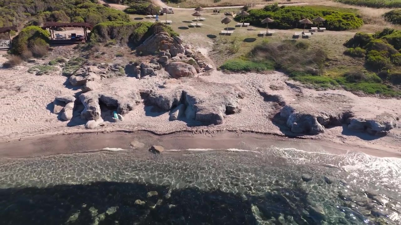 Widok z lotu ptaka skalistego wybrzeża i piaszczystej plaży z parasolami przeciwsłonecznymi w pobliżu czystej wody morskiej