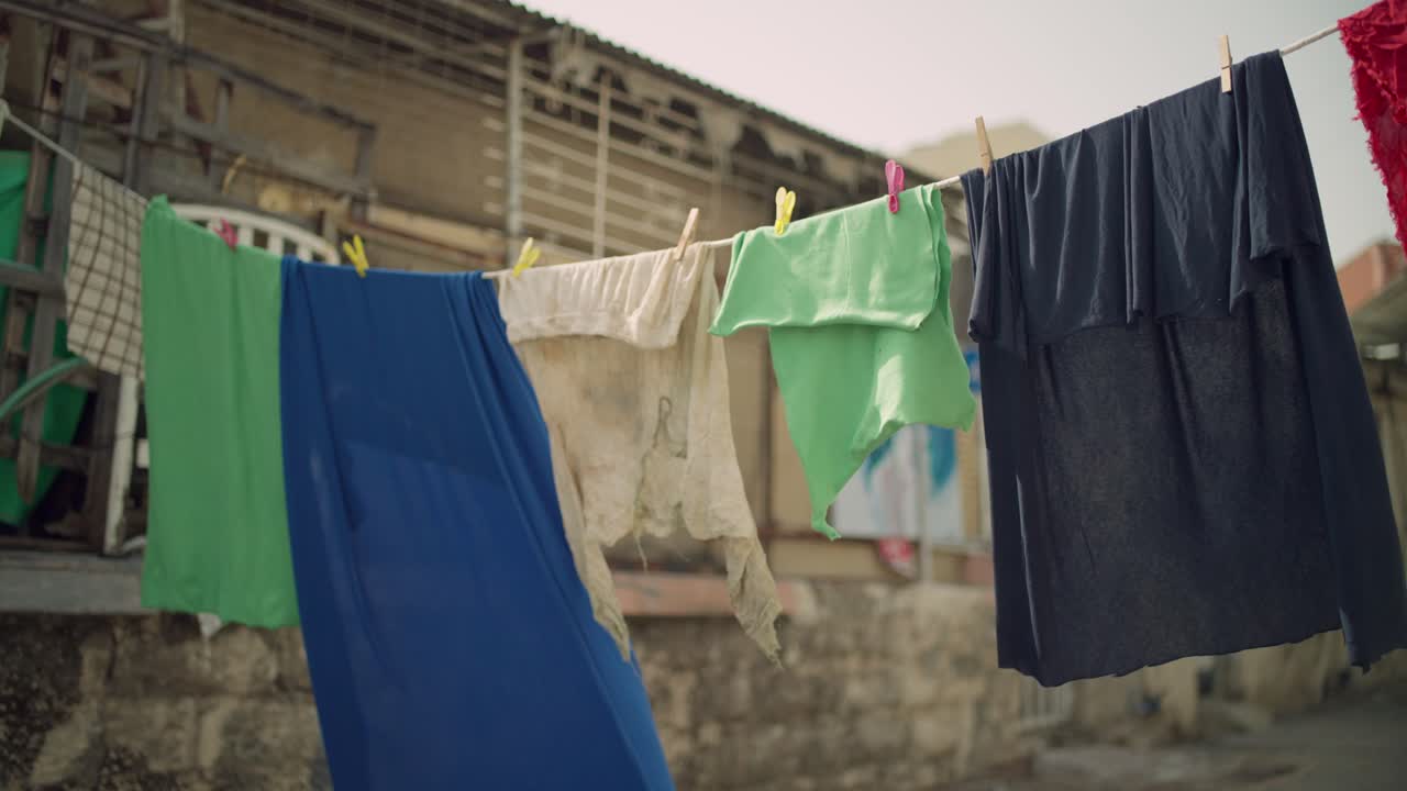 Laundry and fabrics and clothes hang on rope or line in rundown street alley in low income neighborhood or district. Favella or economic crisis in poor area. Hot climate weather as clothes dry in sun