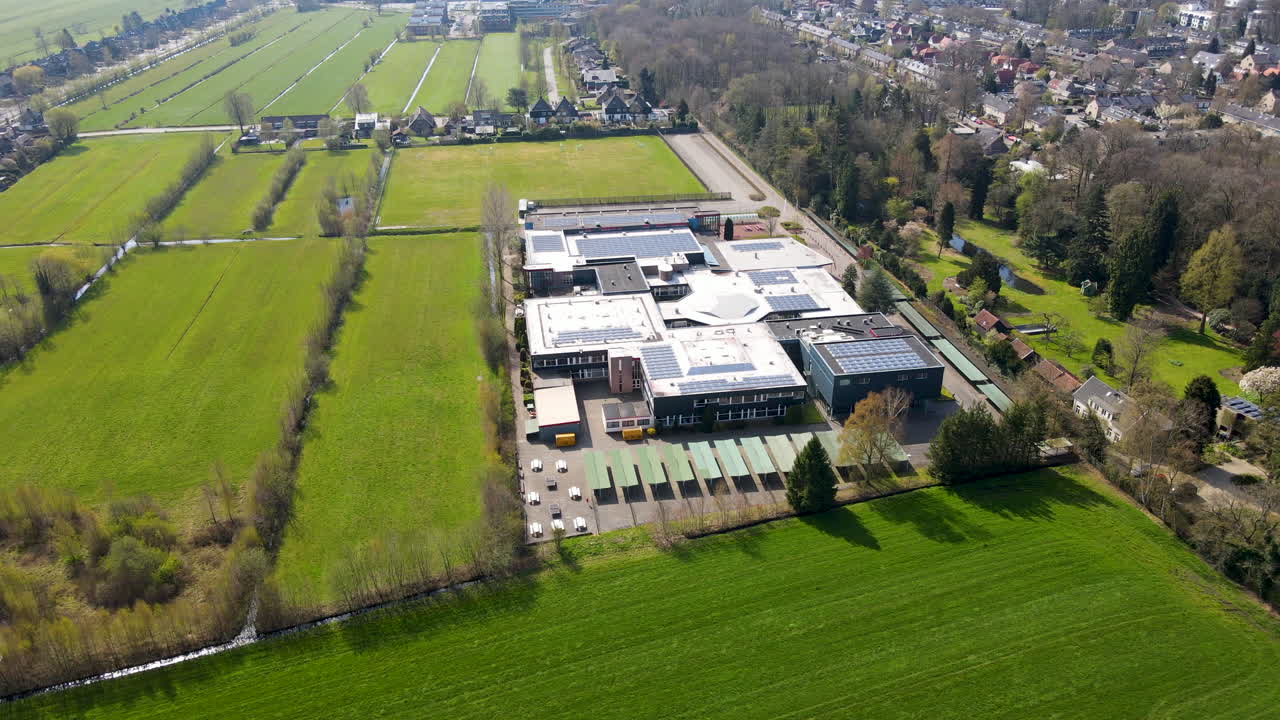 volando hacia una gran escuela secundaria rodeada de verdes prados