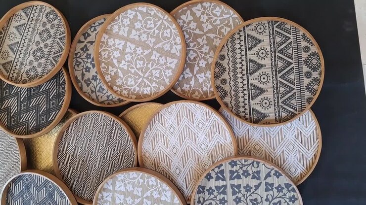 Many round shaped wooden trays with various motifs print on natural fiber weaving