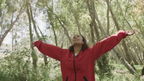 feliz mujer afroamericana extendiendo los brazos en el bosque, cámara lenta