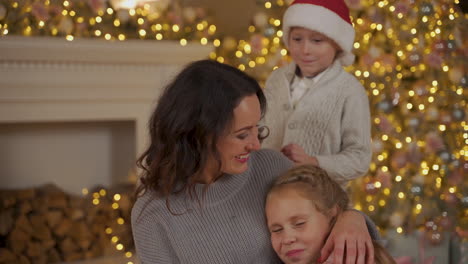 madre, niño y niña se abrazan en navidad