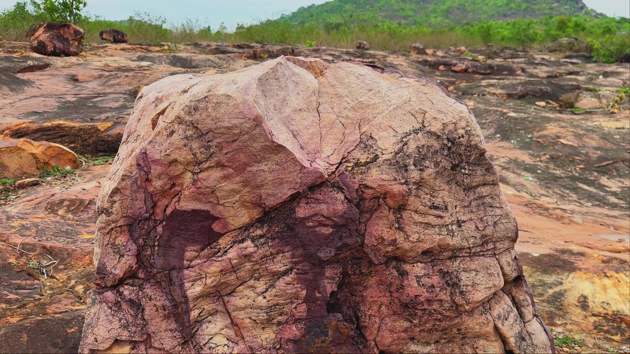 Ripresa orbitante della telecamera che mostra un masso eroso con sorprendenti venature minerali, fratture naturali e texture superficiali colorate che rivelano milioni di anni di cambiamenti geologici