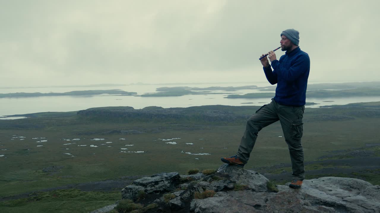Man playing on flute in volcanic landscape