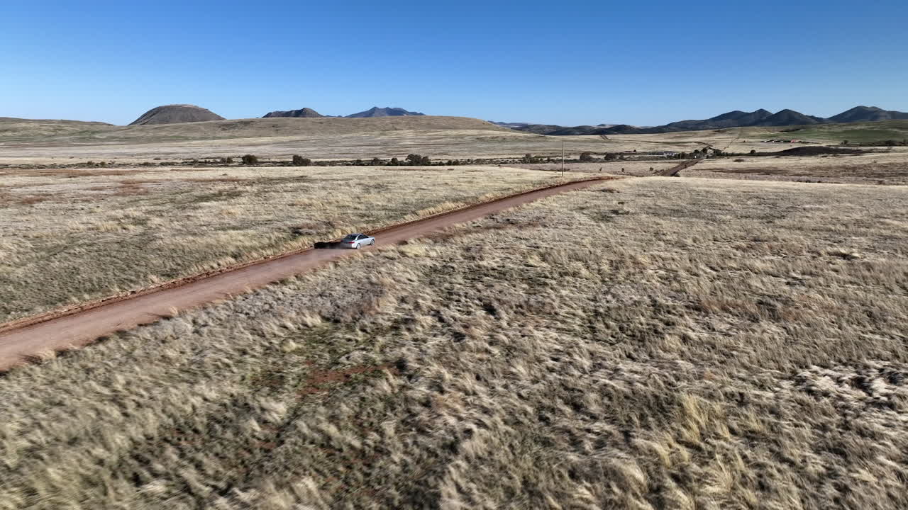 imagen de avión no tripulado de un coche conduciendo en un camino de tierra en willcox, arizona, imagen aérea ascendente