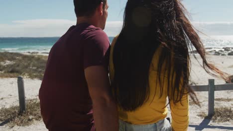 feliz pareja caucásica sentada en un buggy de playa junto al mar hablando