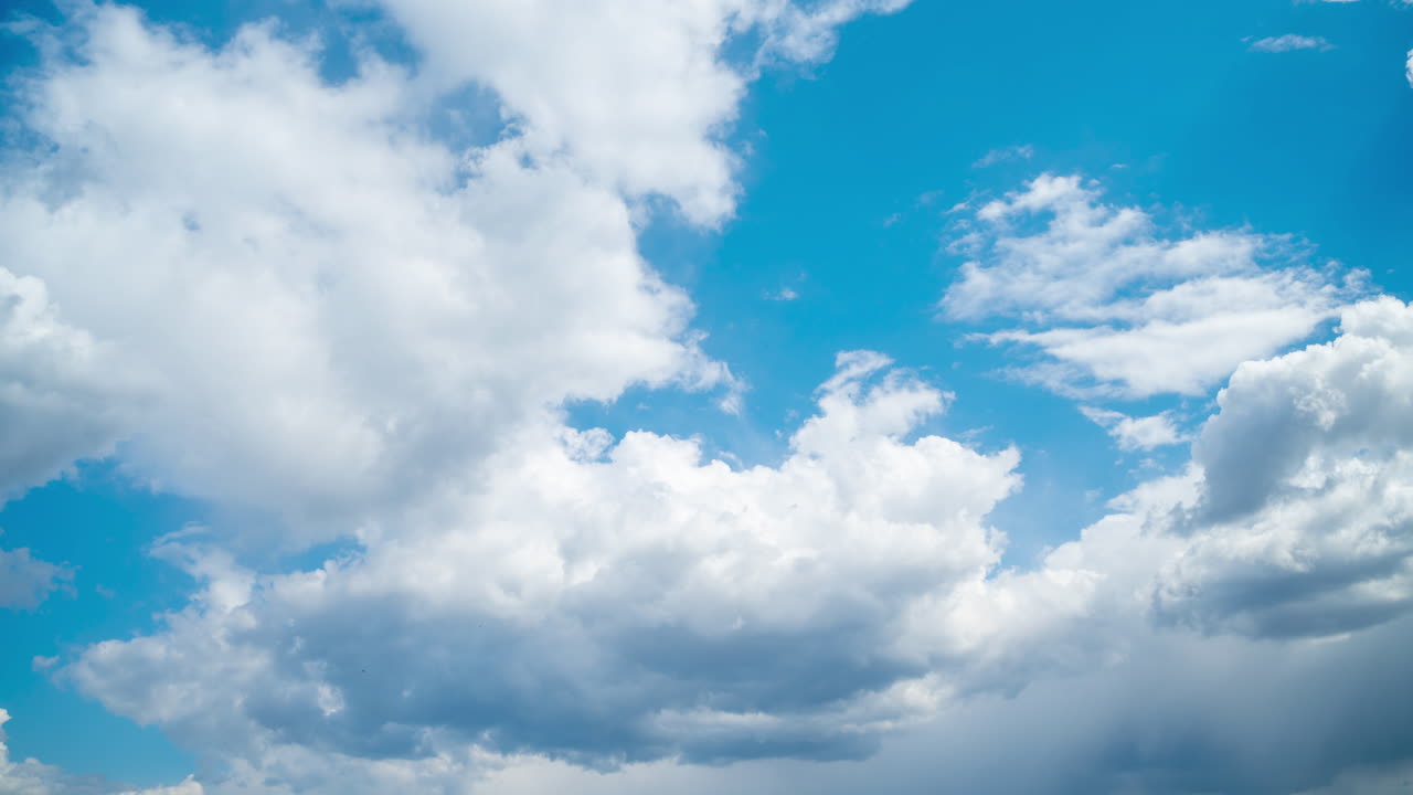 Blue sky with white cumulus clouds. The clear sky is clouded by rainy dark clouds. Summer timelapse
