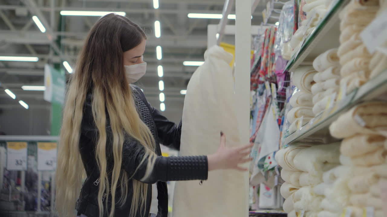 mujer comprando tela en una tienda con una máscara